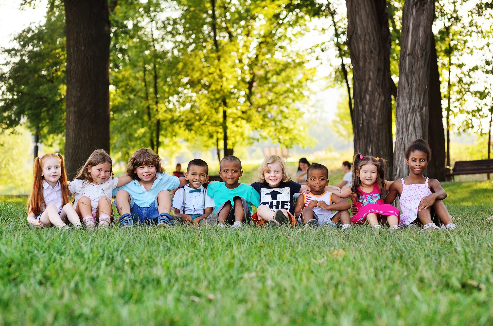 many young children of different races play together in the Park on the green fresh grass.